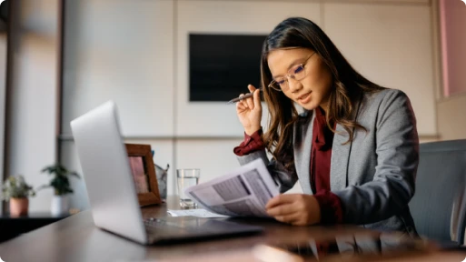 Femme d'affaires concentrée sur des documents, symbolisant le soutien professionnel pour créer son entreprise sans tracas administratifs