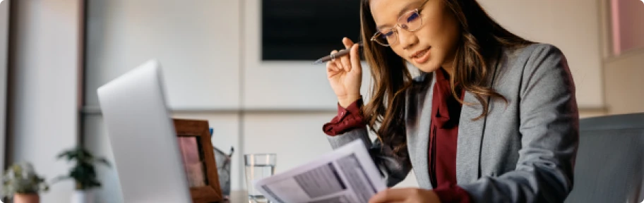 Femme d'affaires concentrée sur des documents, symbolisant le soutien professionnel pour créer son entreprise sans tracas administratifs.