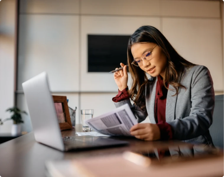 Femme d'affaires concentrée sur des documents, symbolisant le soutien professionnel pour créer son entreprise sans tracas administratifs.