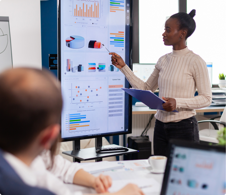 Une femme présente des graphiques sur un écran interactif lors d'une réunion