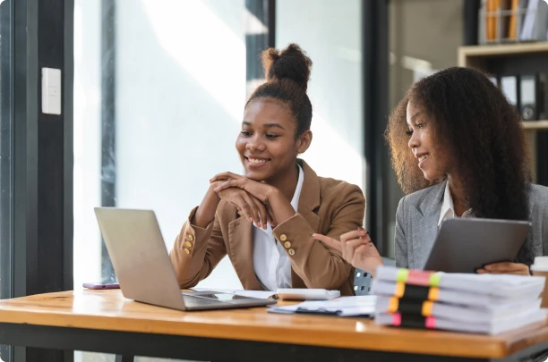 Deux femmes souriant devant un ordinateur portable pour la gestion comptable