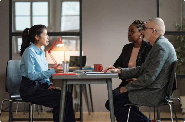 Une femme discutant avec un homme et une femme autour d'une table pour planifier un recrutement